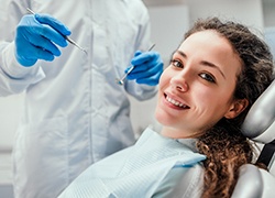 A young woman smiling while undergoing a dental checkup in Herndon