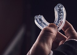 An up-close image of a person holding a customized mouthguard in Herndon