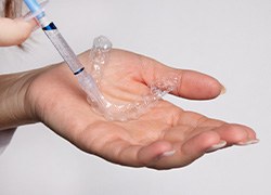 A woman’s hand holding a professional take home whitening kit