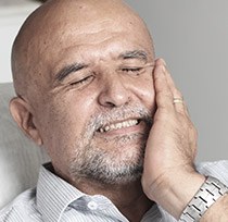 Man in dental chair holding jaw