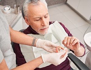 Dentist handing dentures to man in dental chair