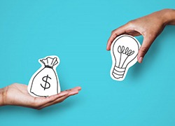 One hand holding a bag of money while another holds a lightbulb 