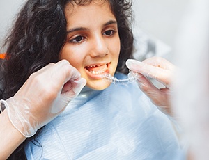Dentist putting clear aligner on teenage girl