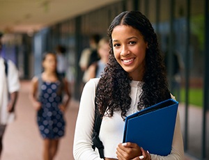 Teenage girl smiling while holding blue binder