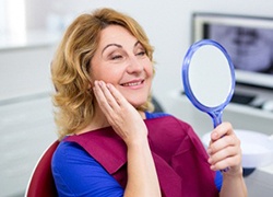 woman admiring her new smile in a mirror