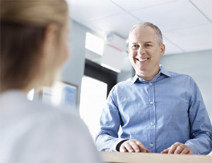 An older man speaking with a dental employee.