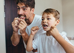 A father and son flossing their teeth in the bathroom in Herndon