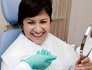 Woman in dental chair holding mirror