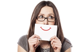 A woman holding a fake smile in front of her mouth