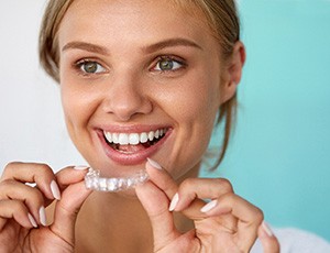 Patient smiling while holding teeth whitening tray