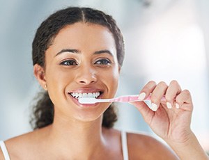 Closeup of woman smiling while brushing her teeth