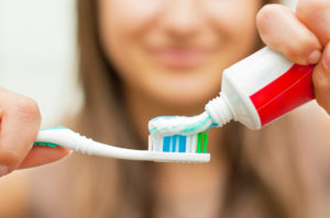 woman smiling applying toothpaste to toothbrush