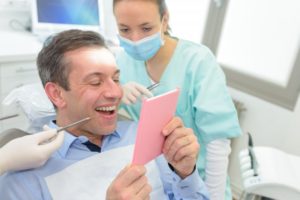 a man looking at his smile in the dentist chair