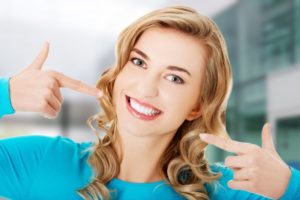 a young woman pointing at her smile