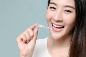 a young woman holding an Invisalign aligner