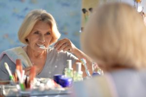 an older woman standing in front of the mirror brushing her teeth