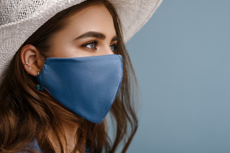 A woman wearing a hat and cloth face mask