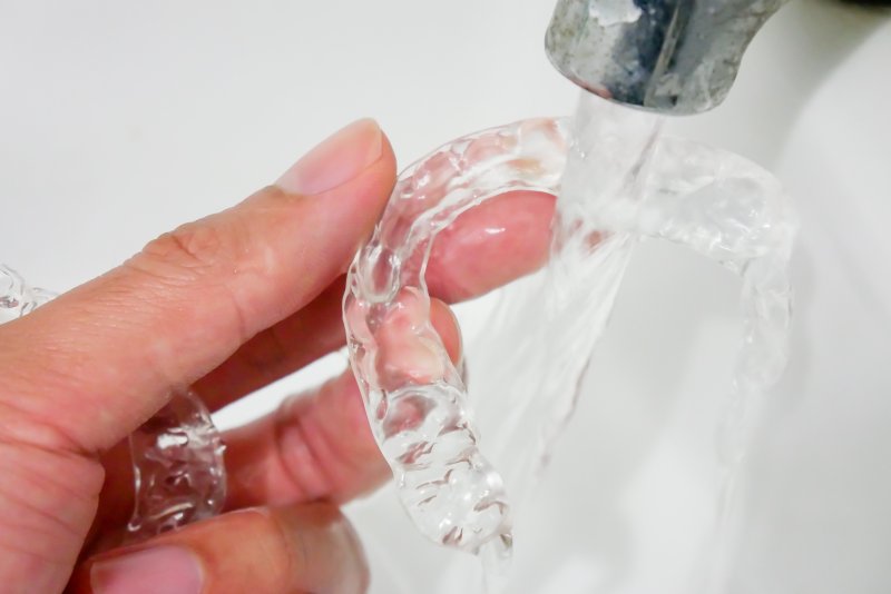 an up-close look at person cleaning their Invisalign aligners with water