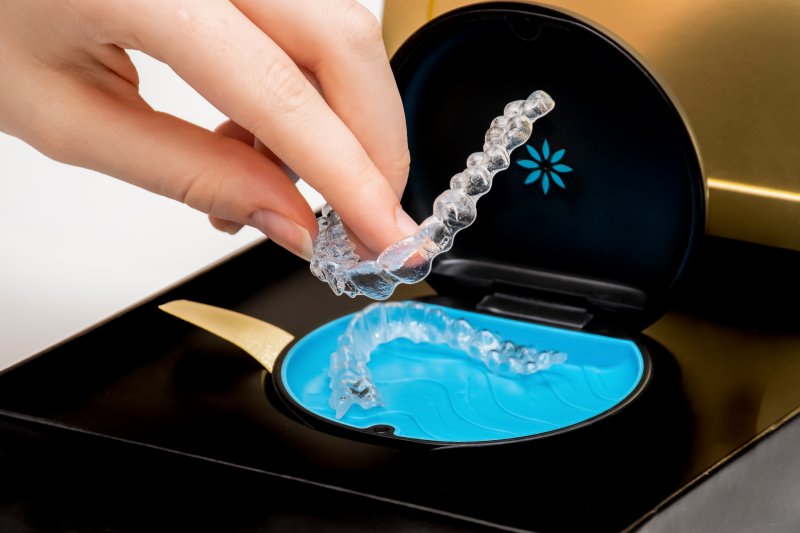 person grabbing Invisalign aligner