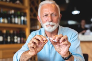 Senior man breaking a cigarette in half