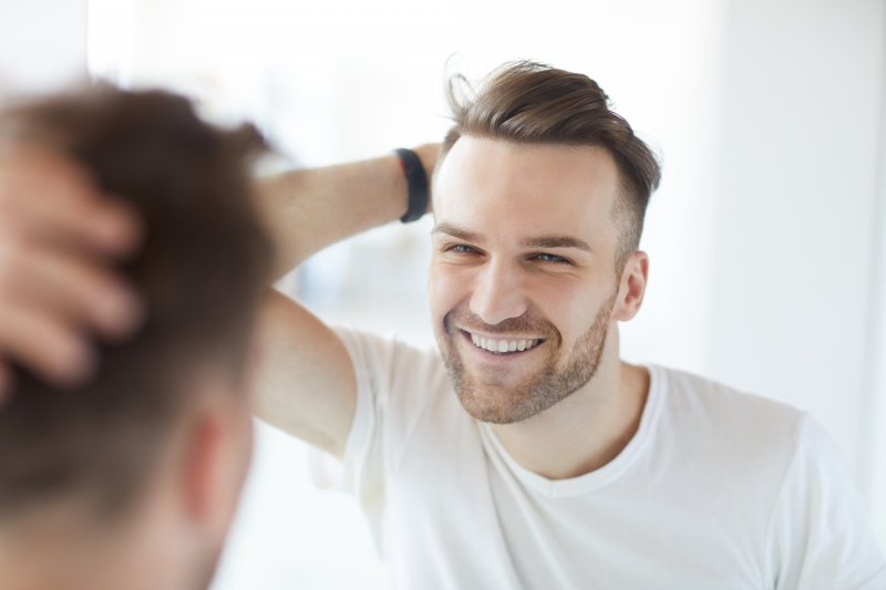A man looking in the mirror at his new dental implants