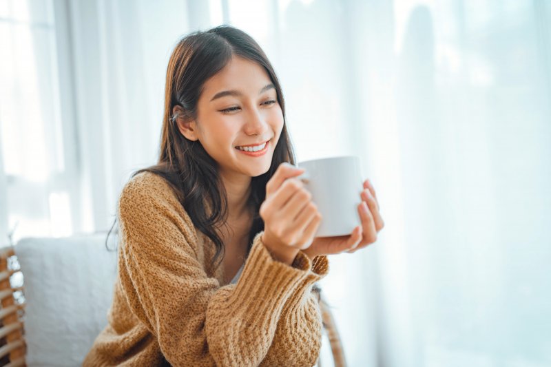 a woman smiling while drinking coffee