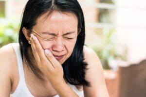 Woman in severe pain holding side of face.