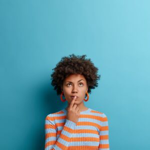 Woman pondering decision with finger to lips and raised eyebrow.